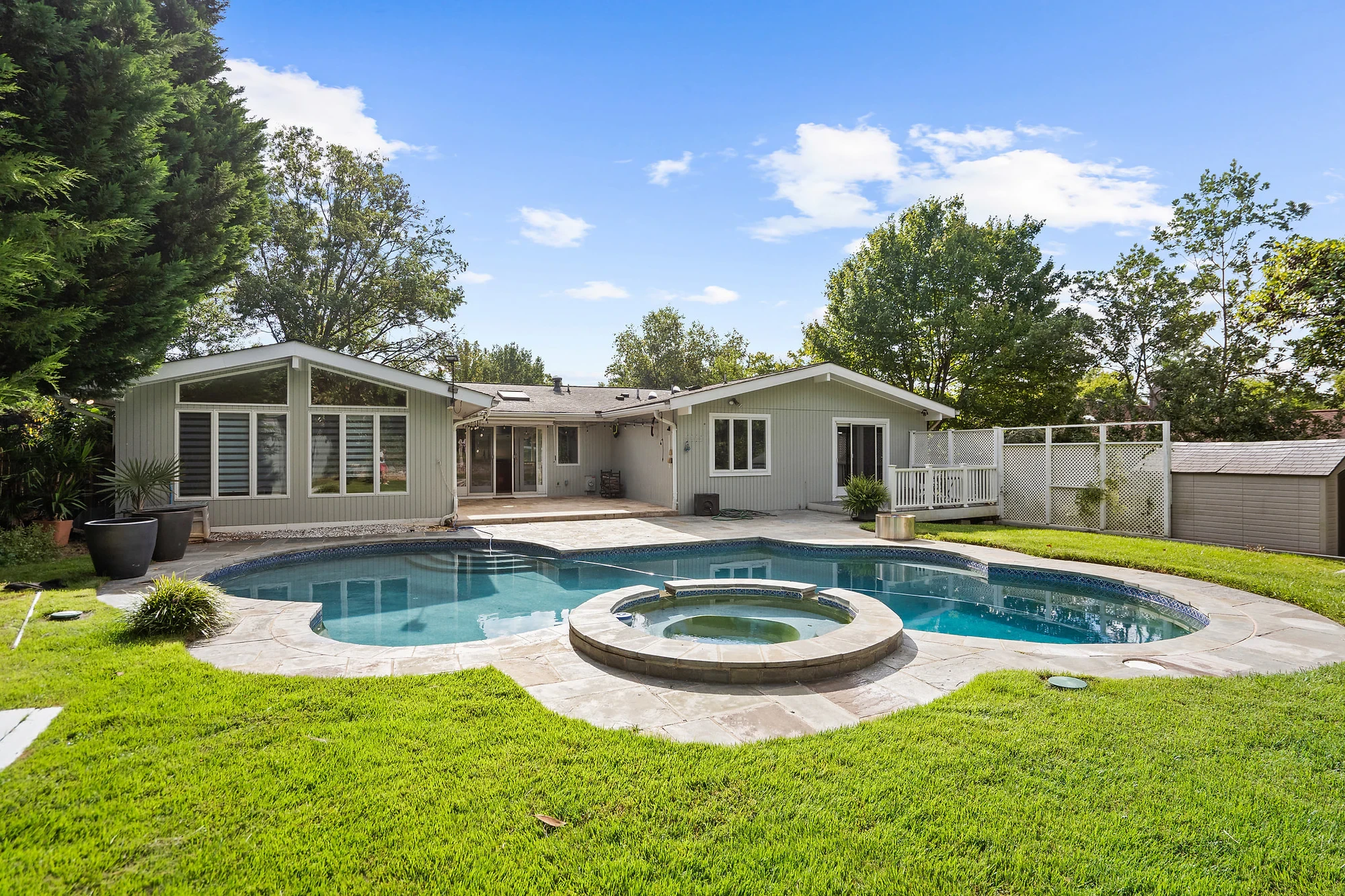Daytime backyard of a ranch home with a kidney-shaped pool and spa — before virtual twilight