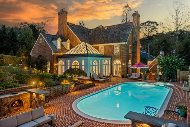 Twilight exterior of a brick colonial home in the DMV with illuminated pool and patio — professional real estate photography