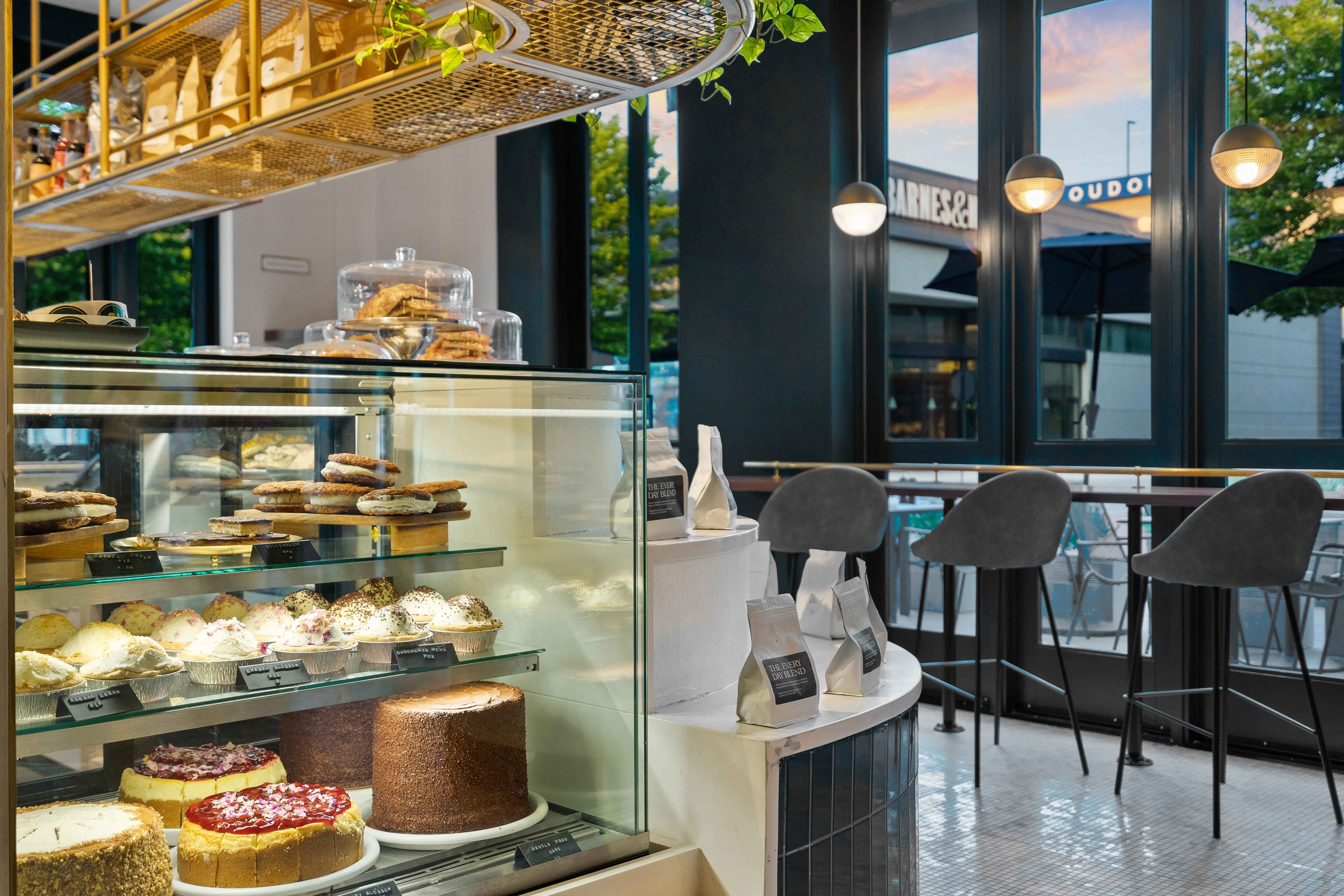Café interior with pastry display case, coffee bar, and window seating — commercial photography