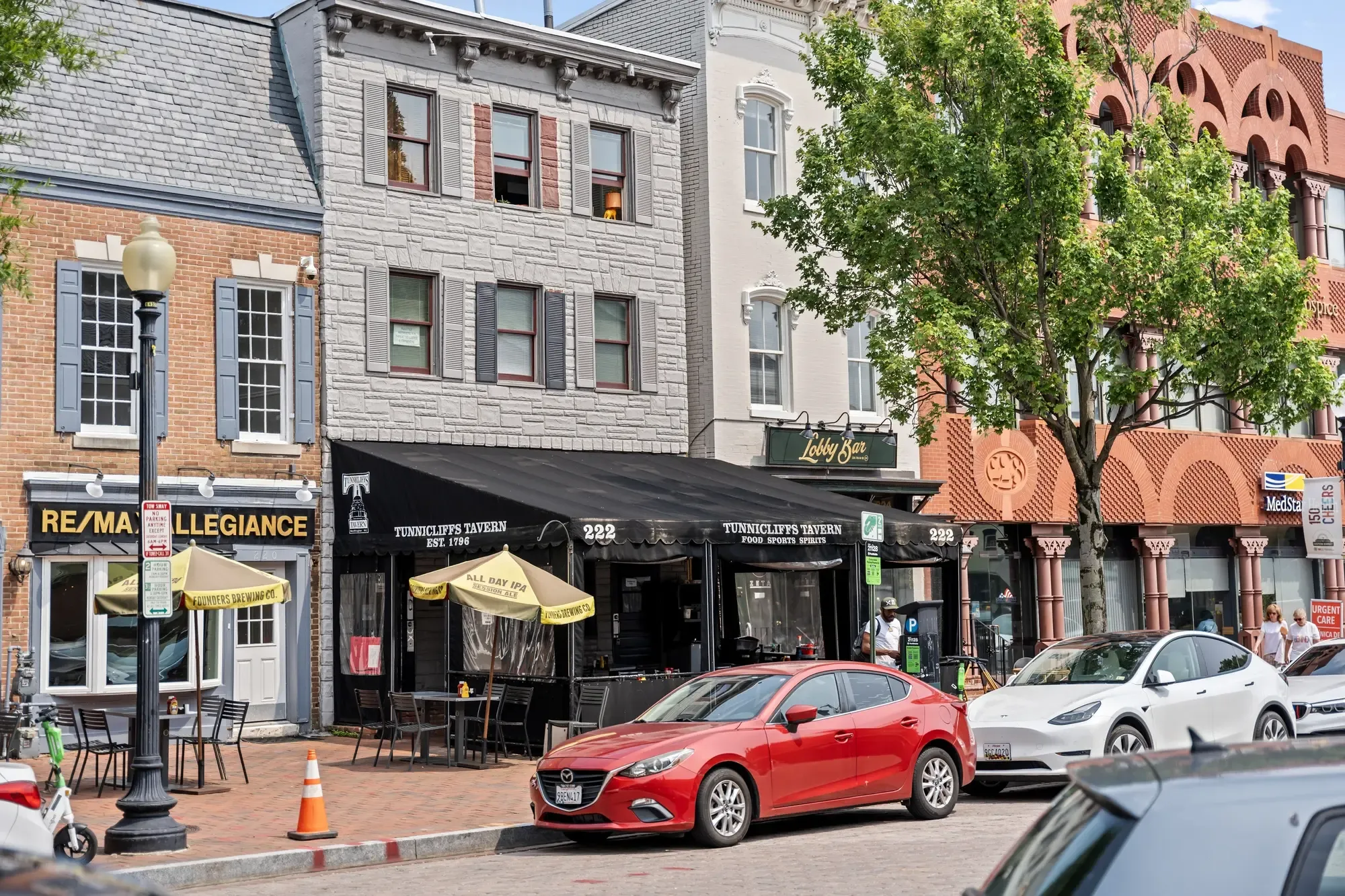 Capitol Hill streetscape near Eastern Market with Tunnicliffs Tavern, sidewalk cafe umbrellas, and pedestrians — neighborhood photography by Umedia