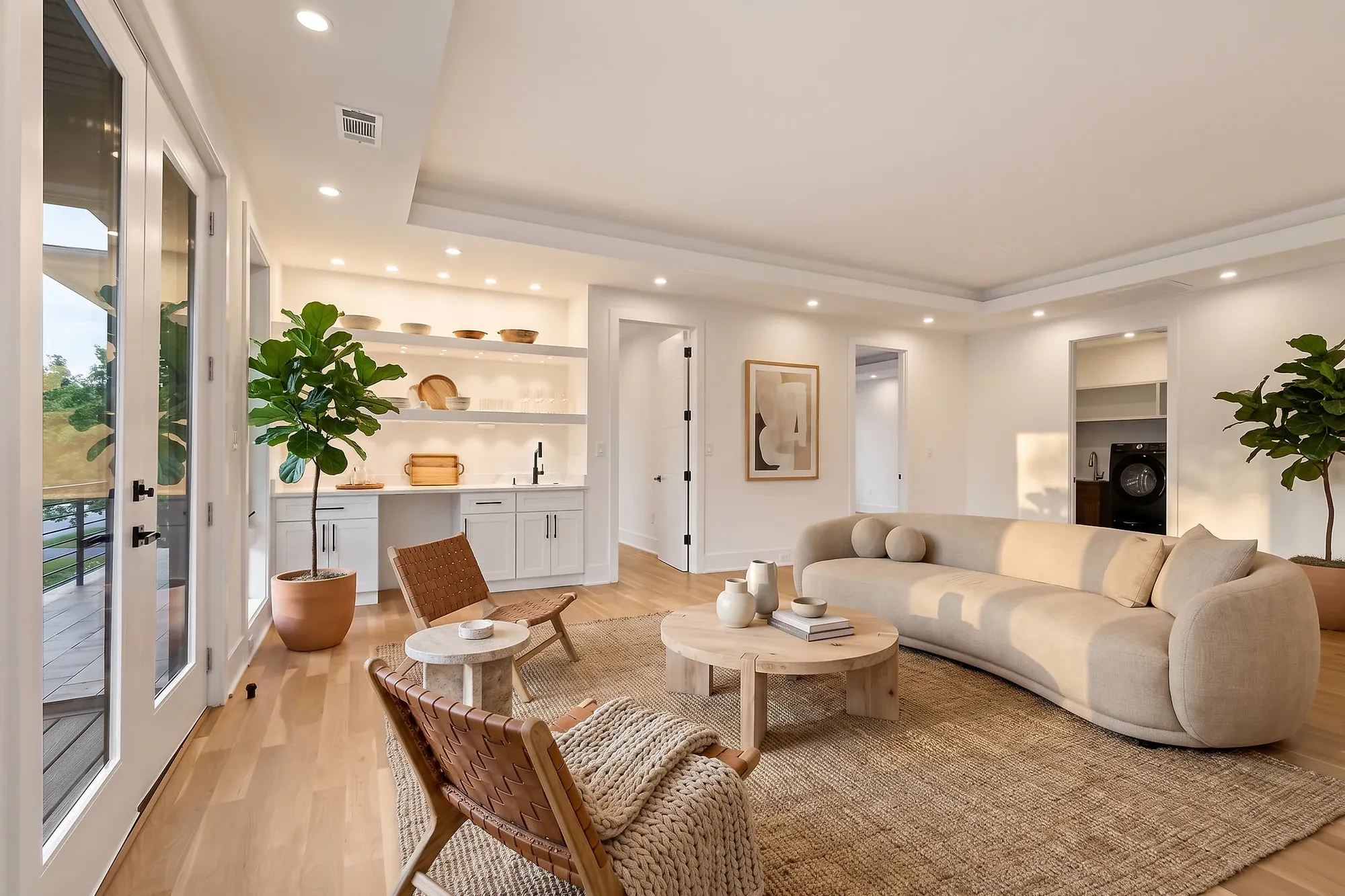The same family room virtually staged with a curved sofa, leather lounge chairs, and a jute rug — after virtual staging by UMedia