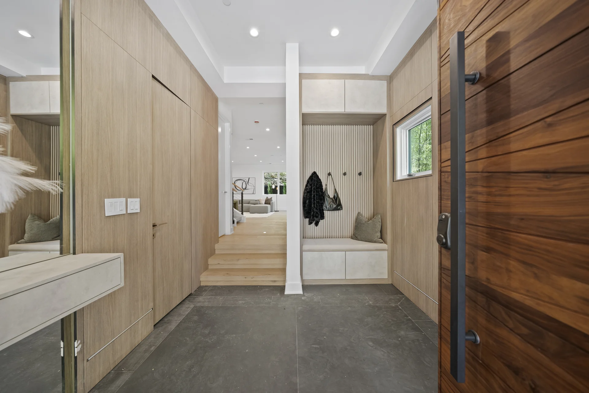 Cinematic real estate videography still — luxury home mudroom entry with walnut door, custom built-in bench, and coat hooks by Umedia