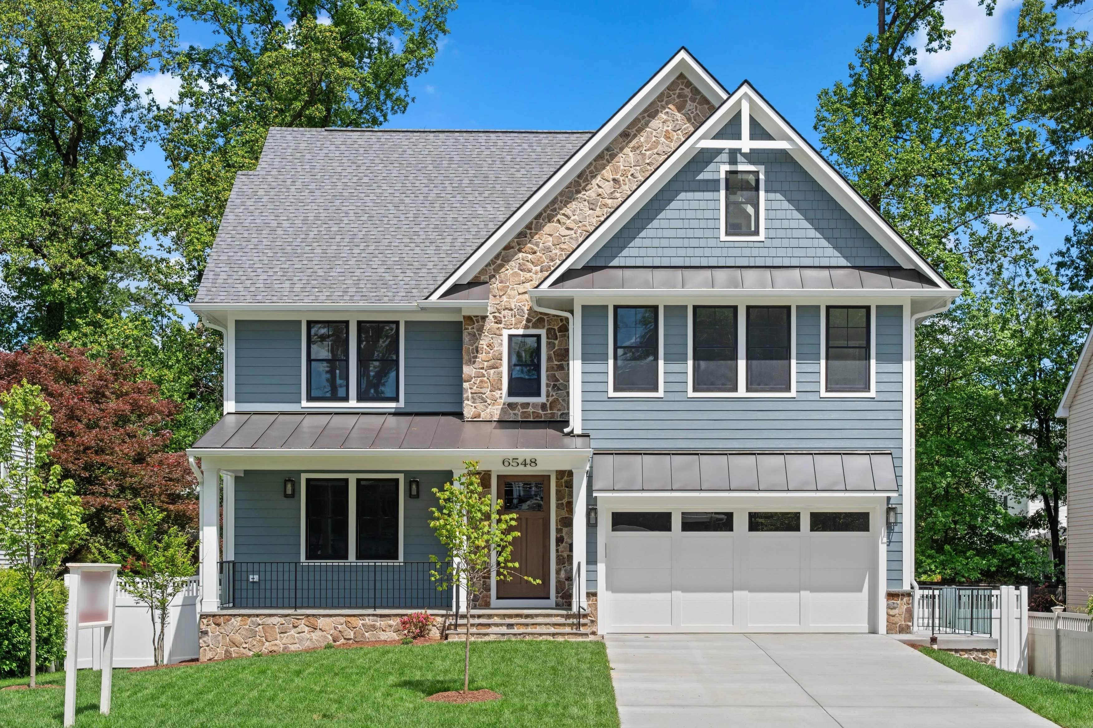 Modern craftsman-style home with blue siding and stone accents
