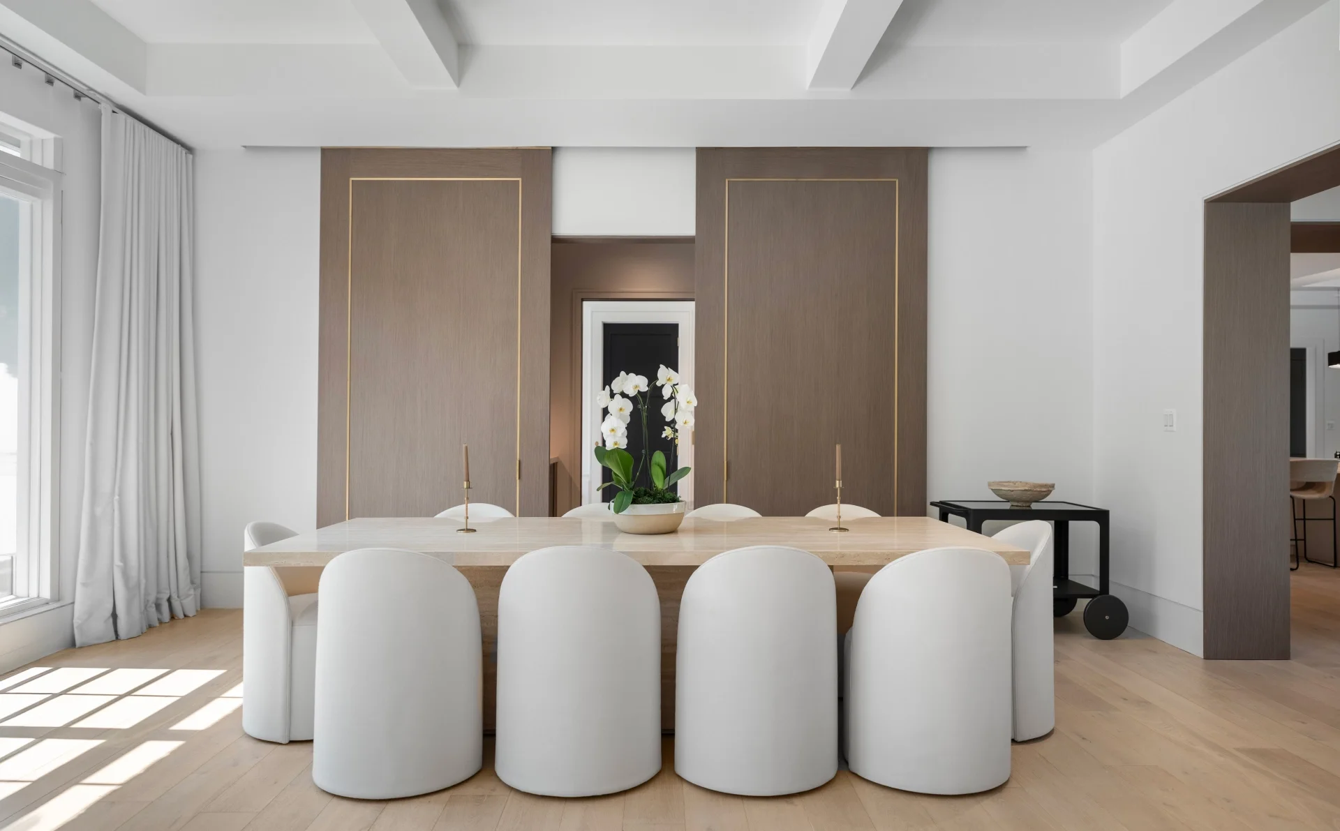 Interior real estate photography of a modern dining room with coffered ceiling and white upholstered chairs in Bethesda Maryland by Umedia