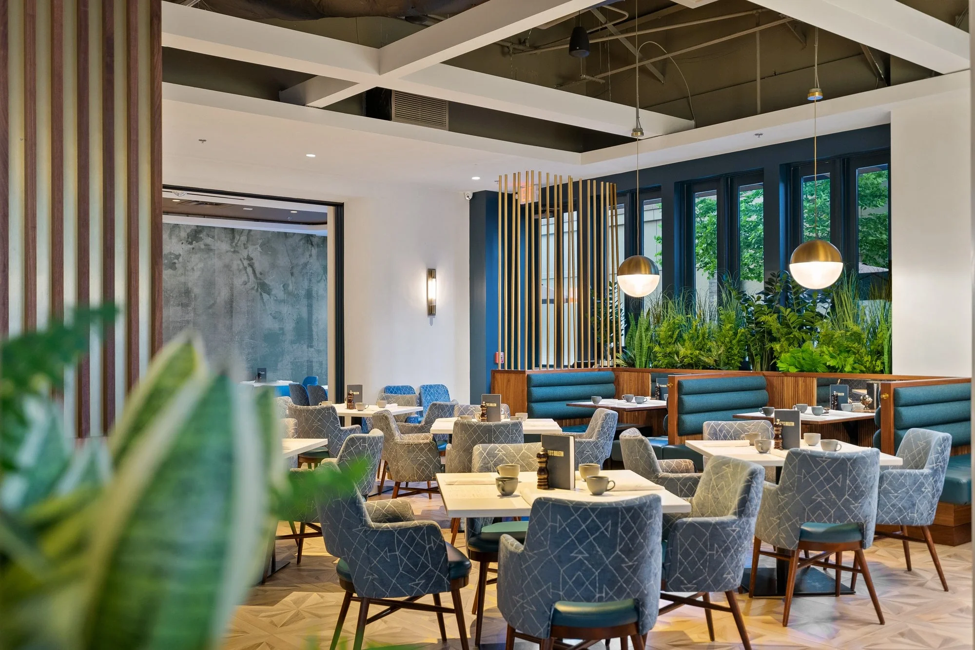 Commercial interior photography of a modern restaurant with blue velvet booths, coffered ceiling, and globe pendant lighting by Umedia