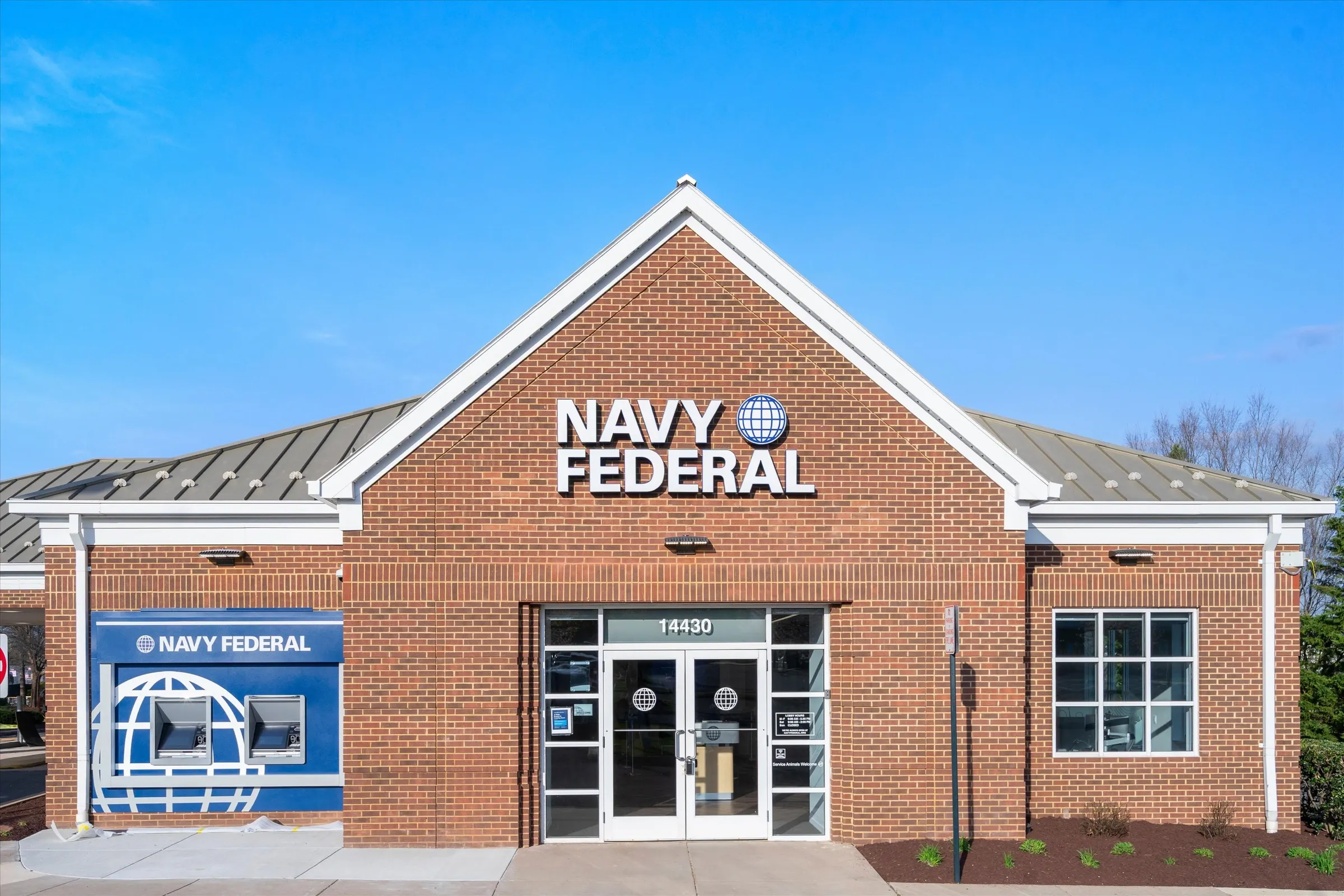 Navy Federal Credit Union Chantilly branch front exterior with brick facade, globe logo signage, ATM kiosk, and glass entry doors at 14430 Chantilly Crossing Lane