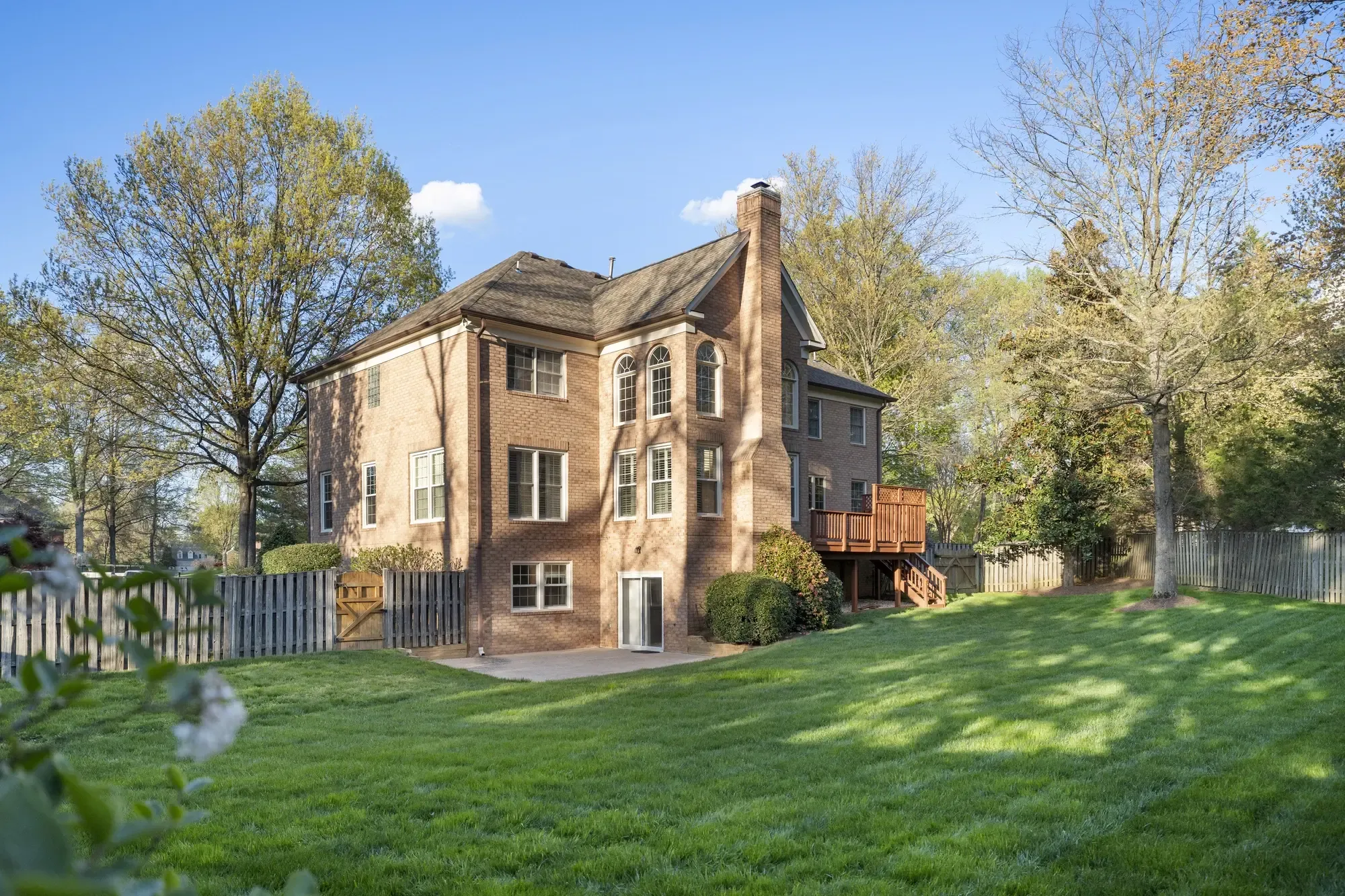 Large fenced backyard and brick exterior rear view
