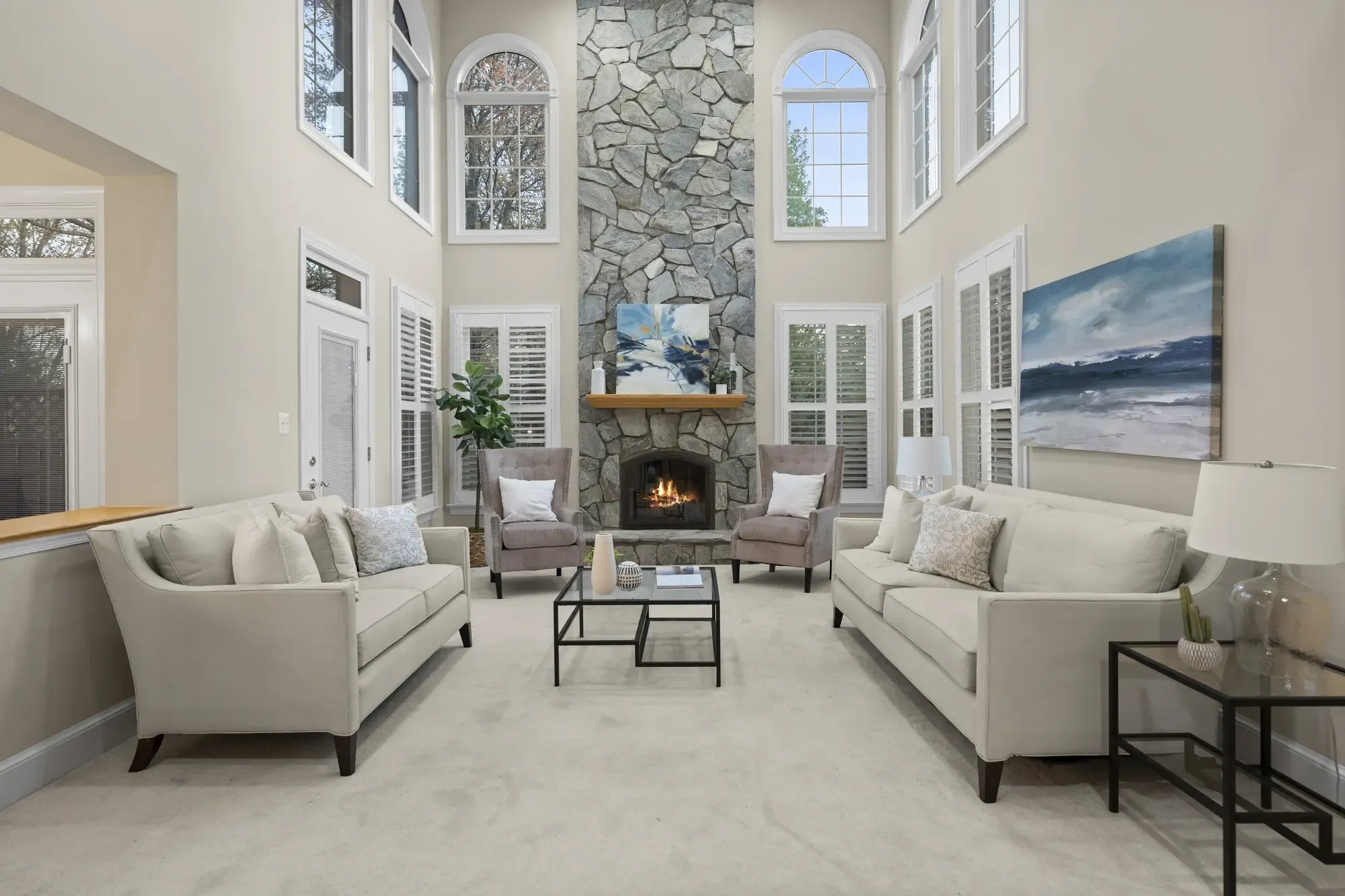 Spacious living room with tall stone fireplace and high ceilings
