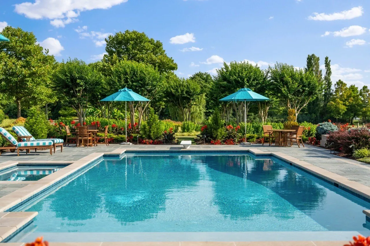 Resort-style backyard pool with spa, striped loungers, and turquoise umbrellas surrounded by lush gardens