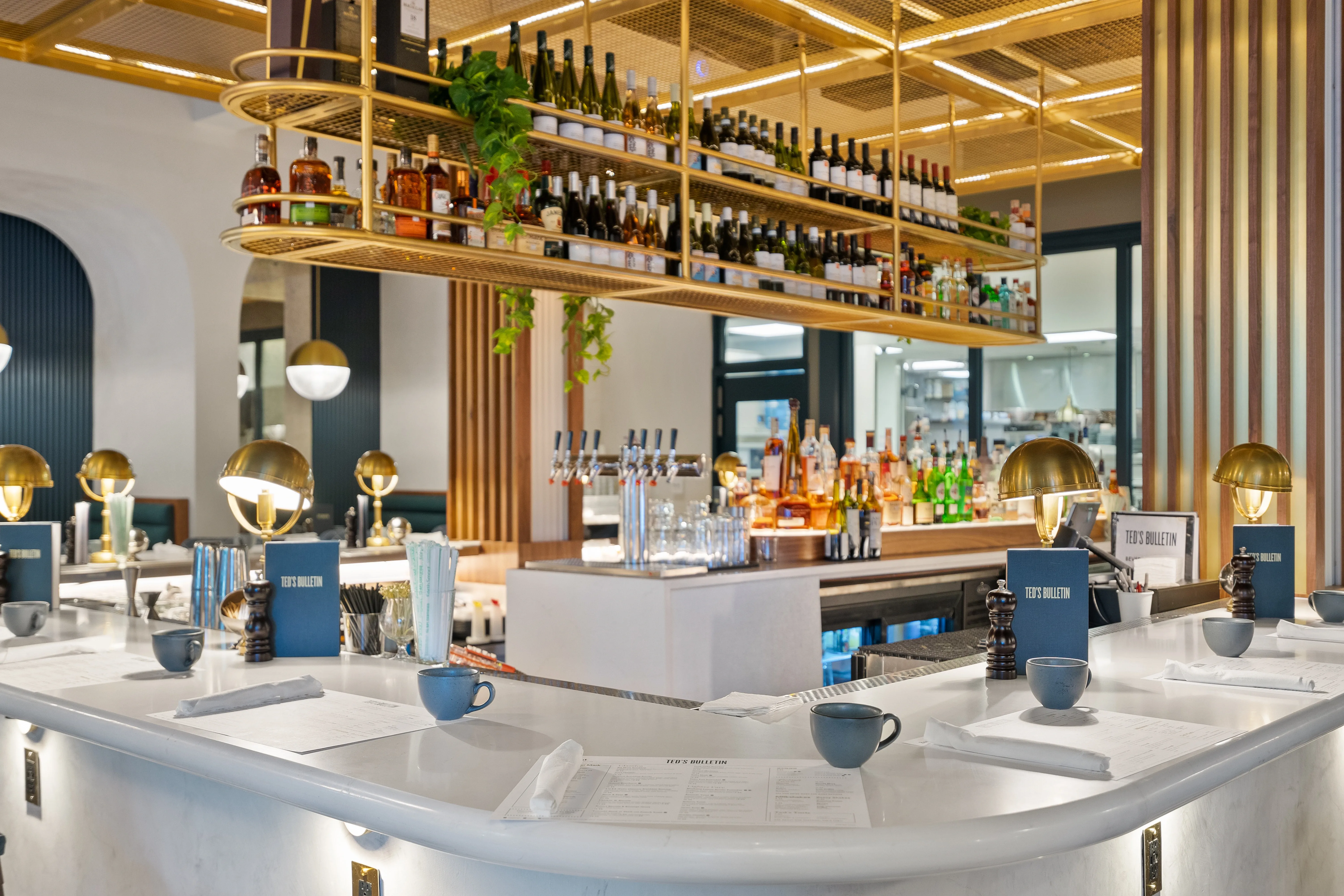 Restaurant bar interior with brass shelving, marble counters, and globe pendant lamps — commercial photography