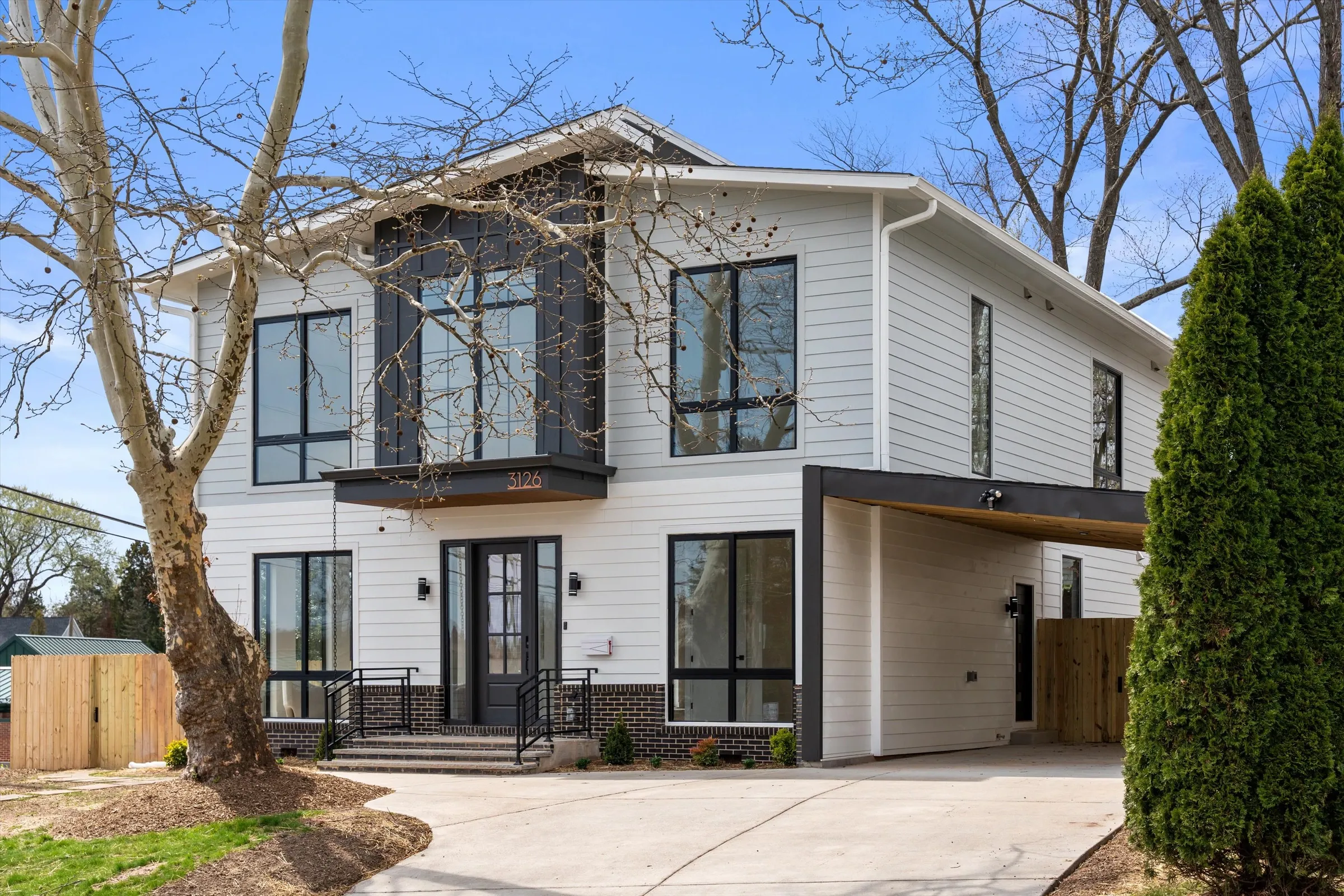 Modern new construction home front exterior at 3126 Westley Rd, Falls Church VA with white siding, black-framed windows, brick accents, and carport
