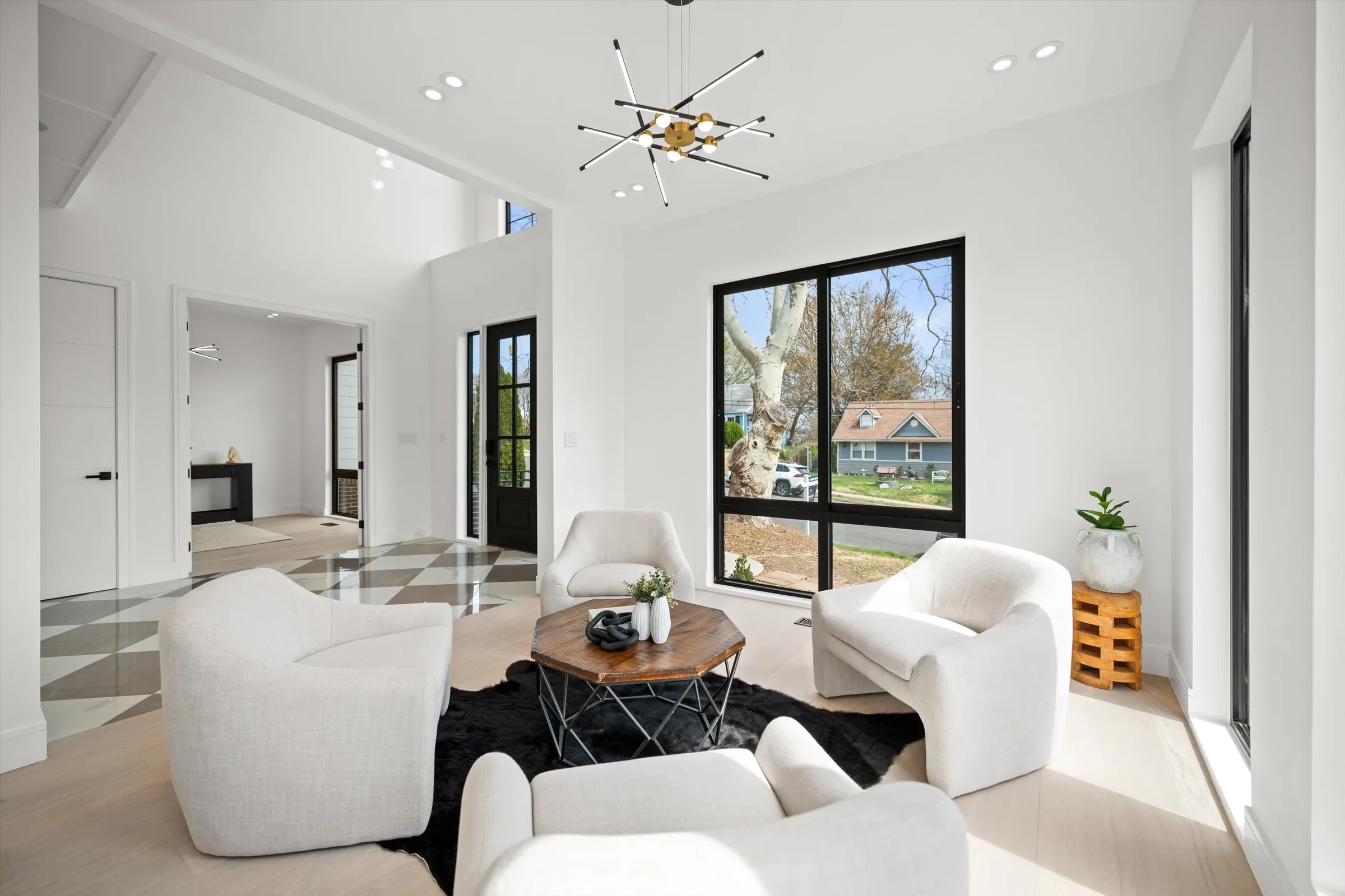 Sitting room wider view showing connection to checkered marble foyer, double-height ceilings, and bright open layout