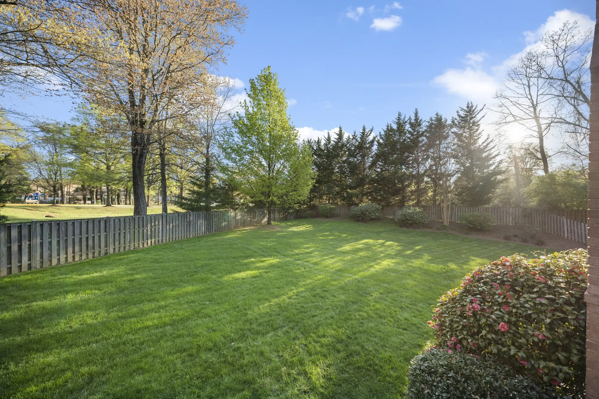 Large fenced backyard with green lawn and mature trees in Oakton VA home photographed by Umedia real estate photography