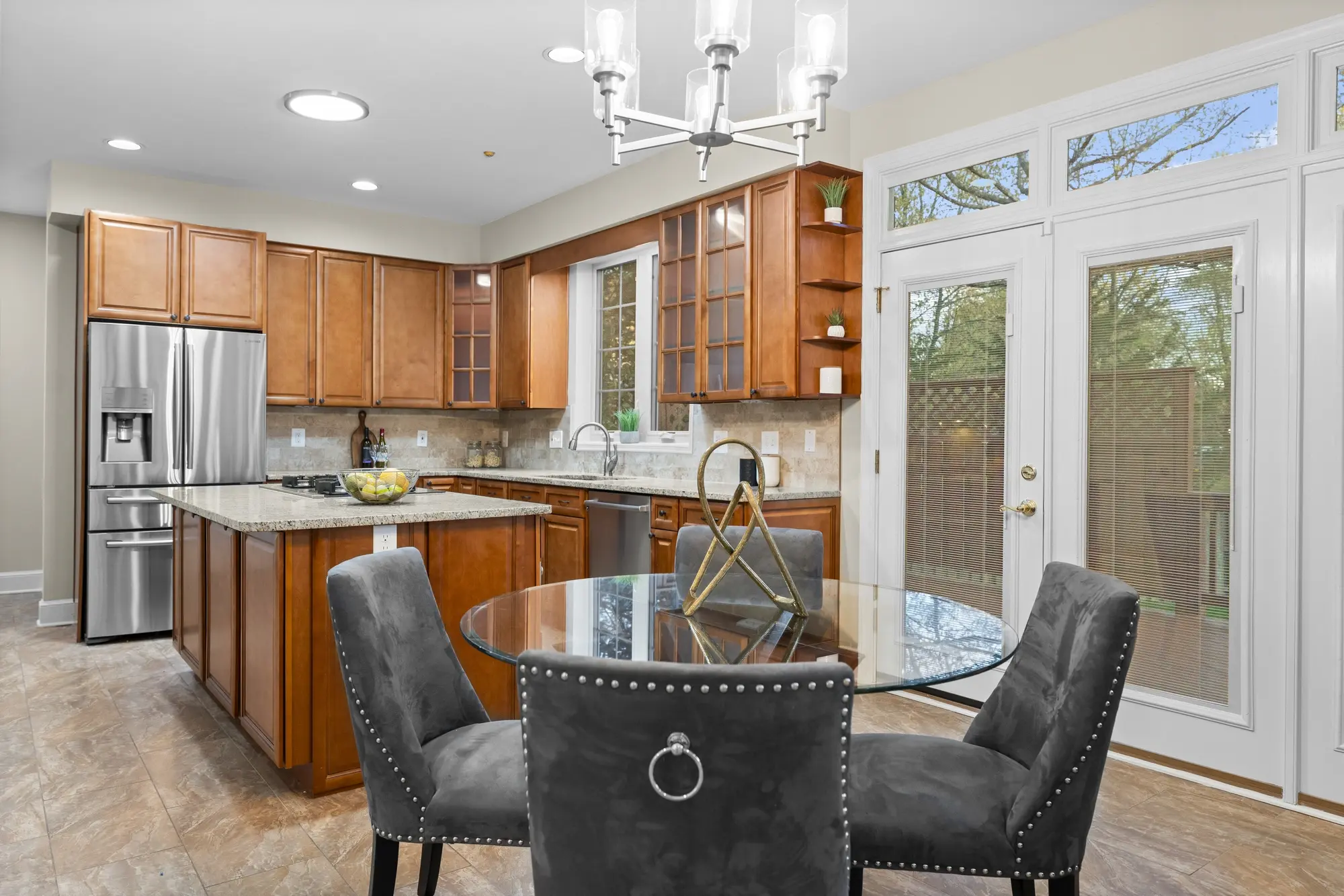 Bright Oakton VA kitchen and dining area with wood cabinetry, stainless steel appliances, and glass table - professional real estate photography by Umedia