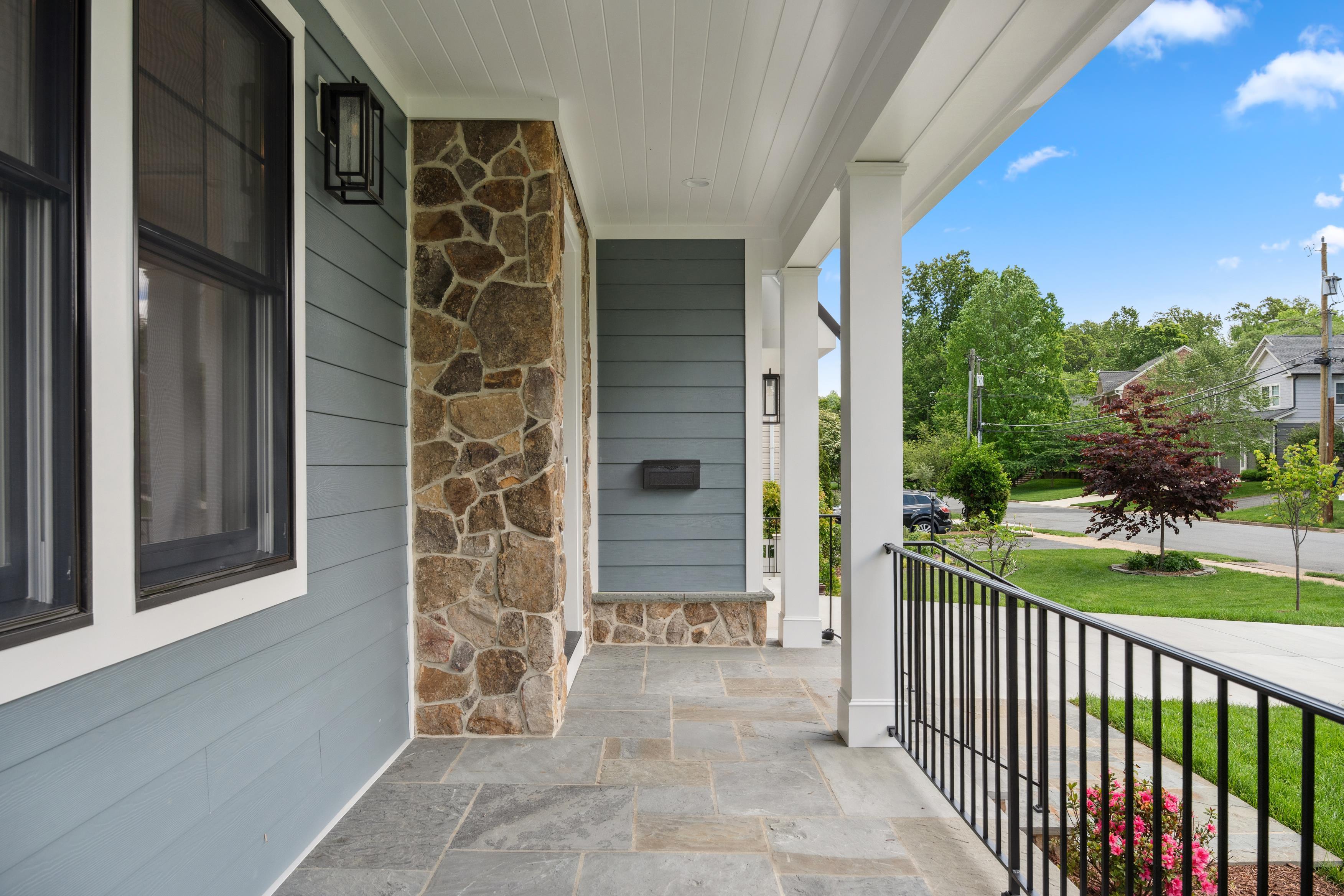 Inviting front porch with stone detail and blue siding, photographed by Umedia for real estate media and marketing in the DMV area
