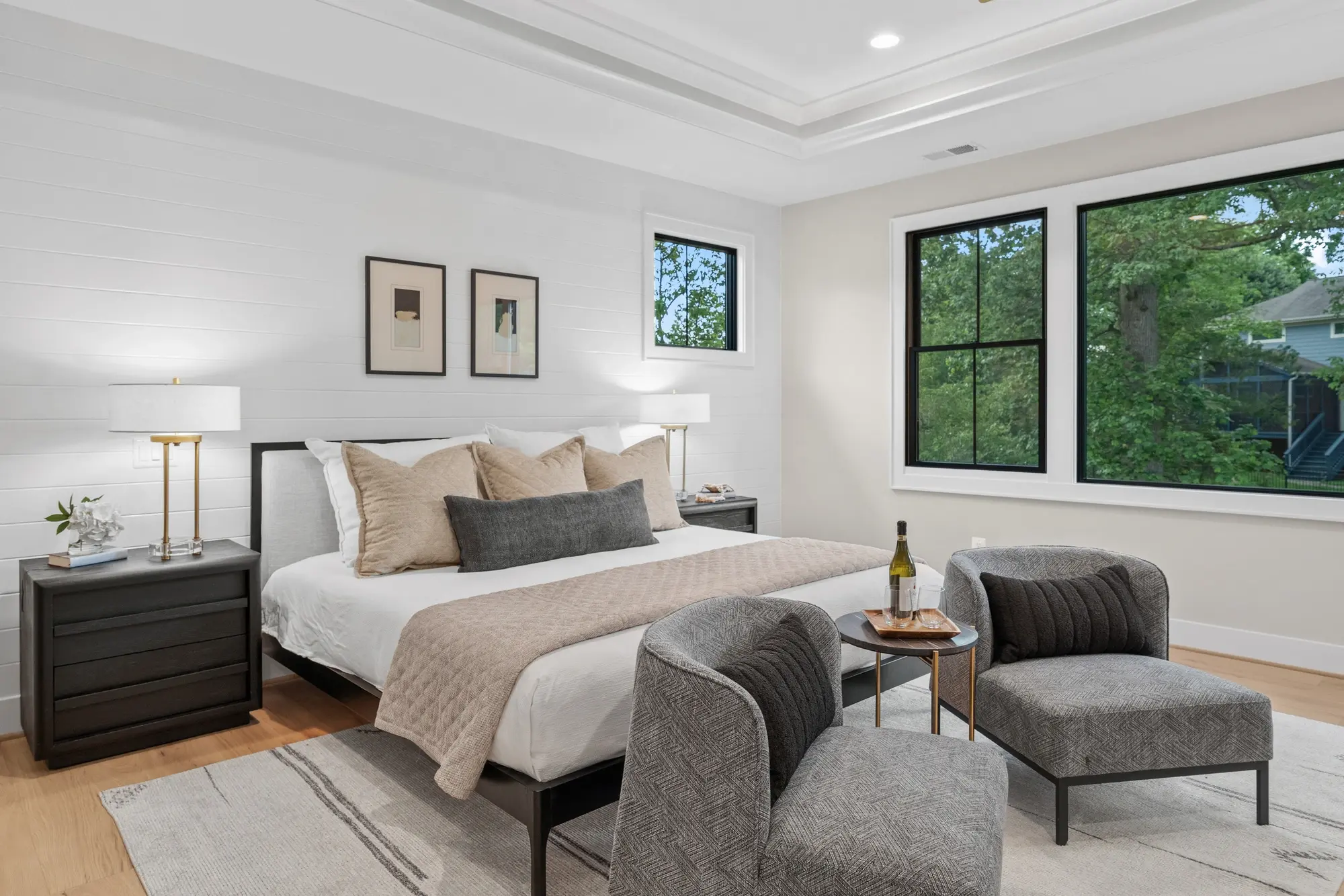 Master bedroom detail with upholstered seating area and black-framed windows