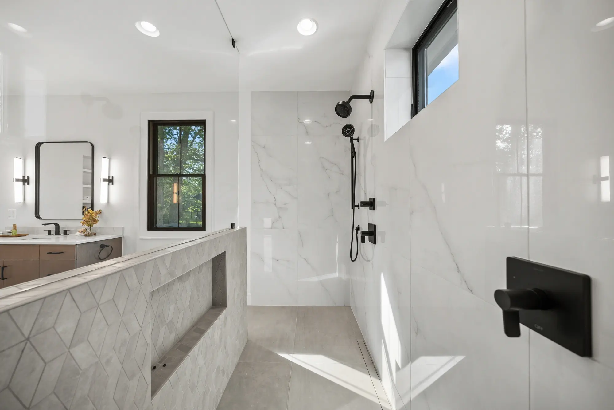 Walk-in shower with marble tile walls, black rain showerhead, and geometric tile accent