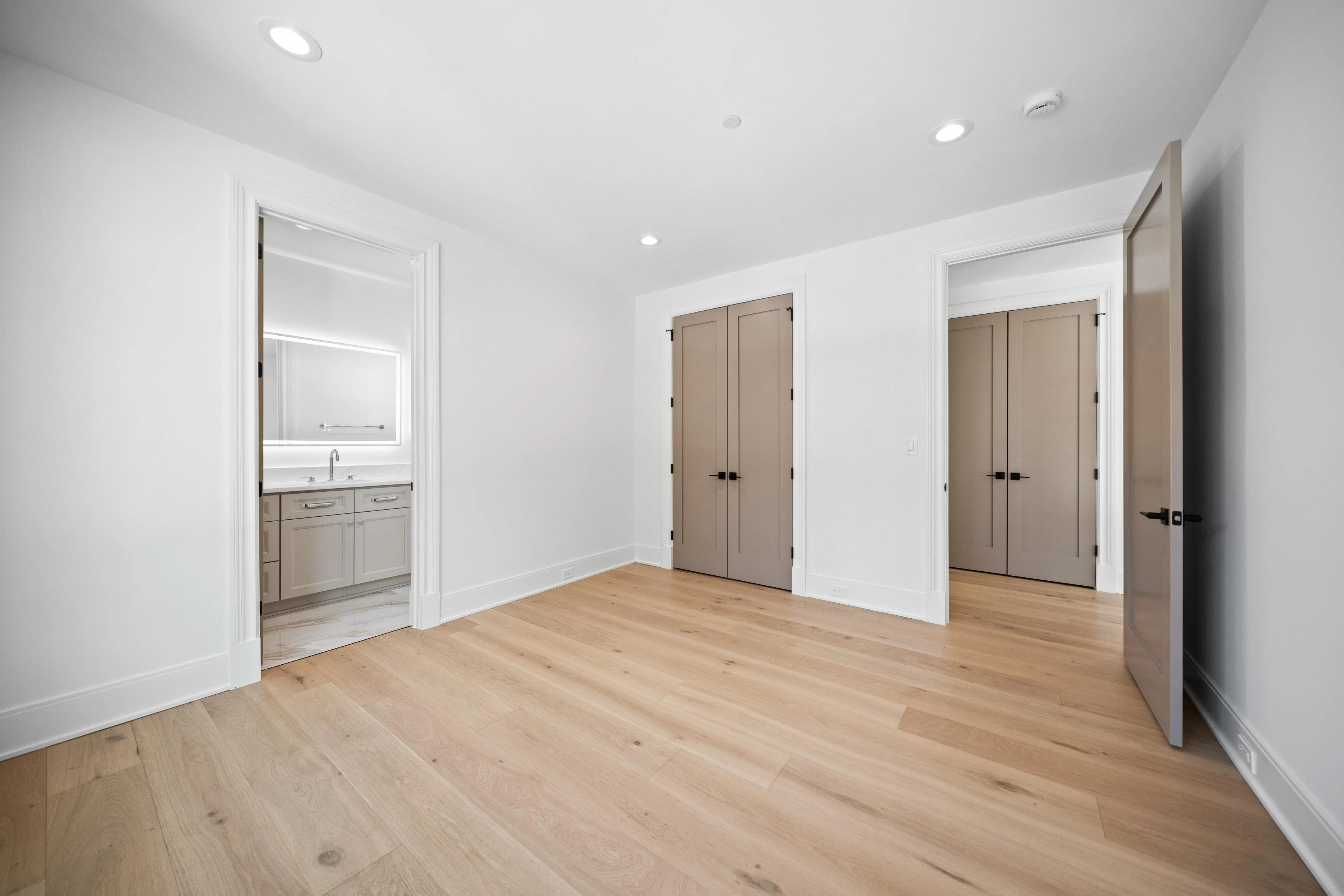 Guest bathroom with warm marble tile walk-in shower, rain showerhead, and LED backlit mirror