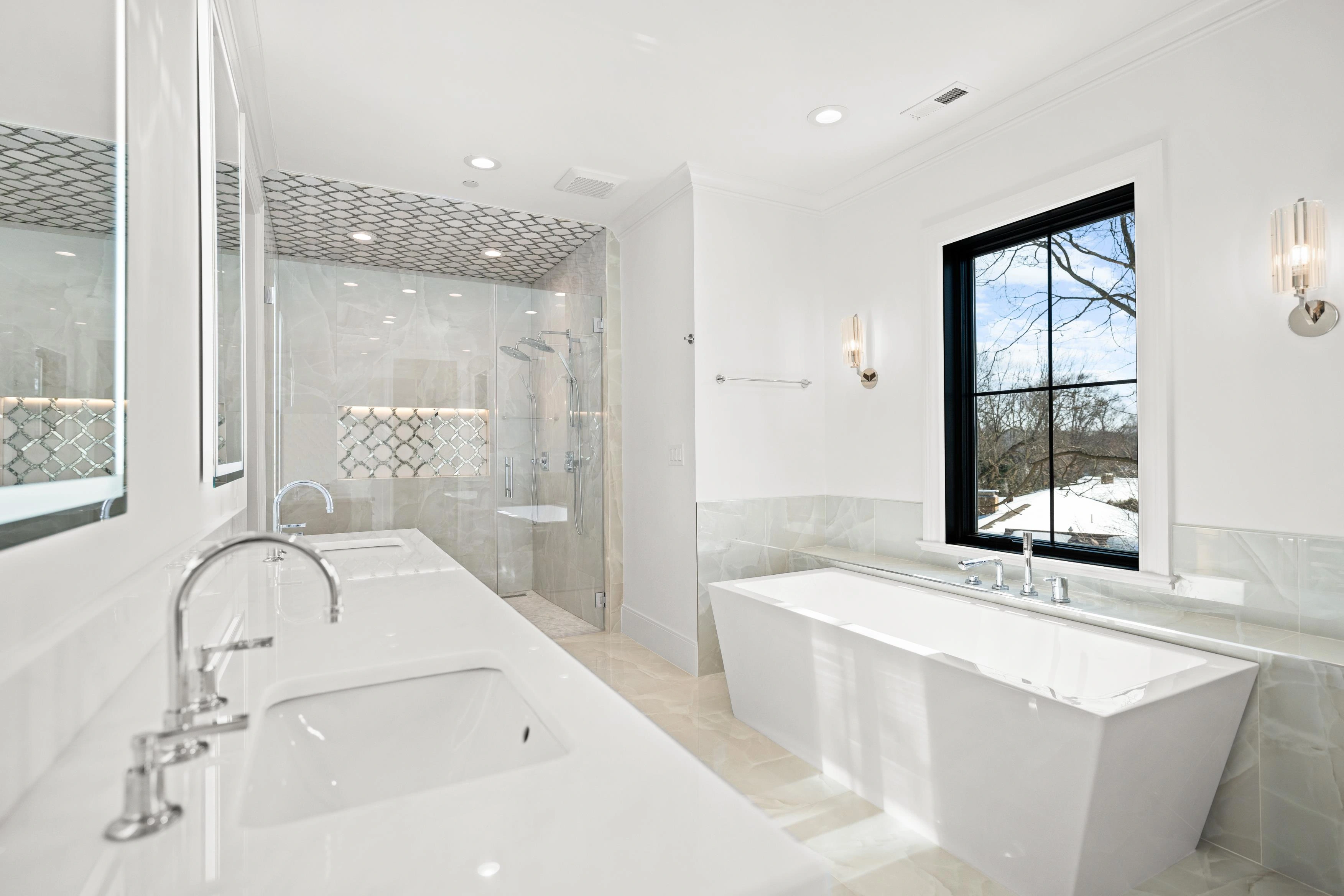 Master bathroom freestanding tub with arabesque tile accent, frameless glass shower, and sconce lighting