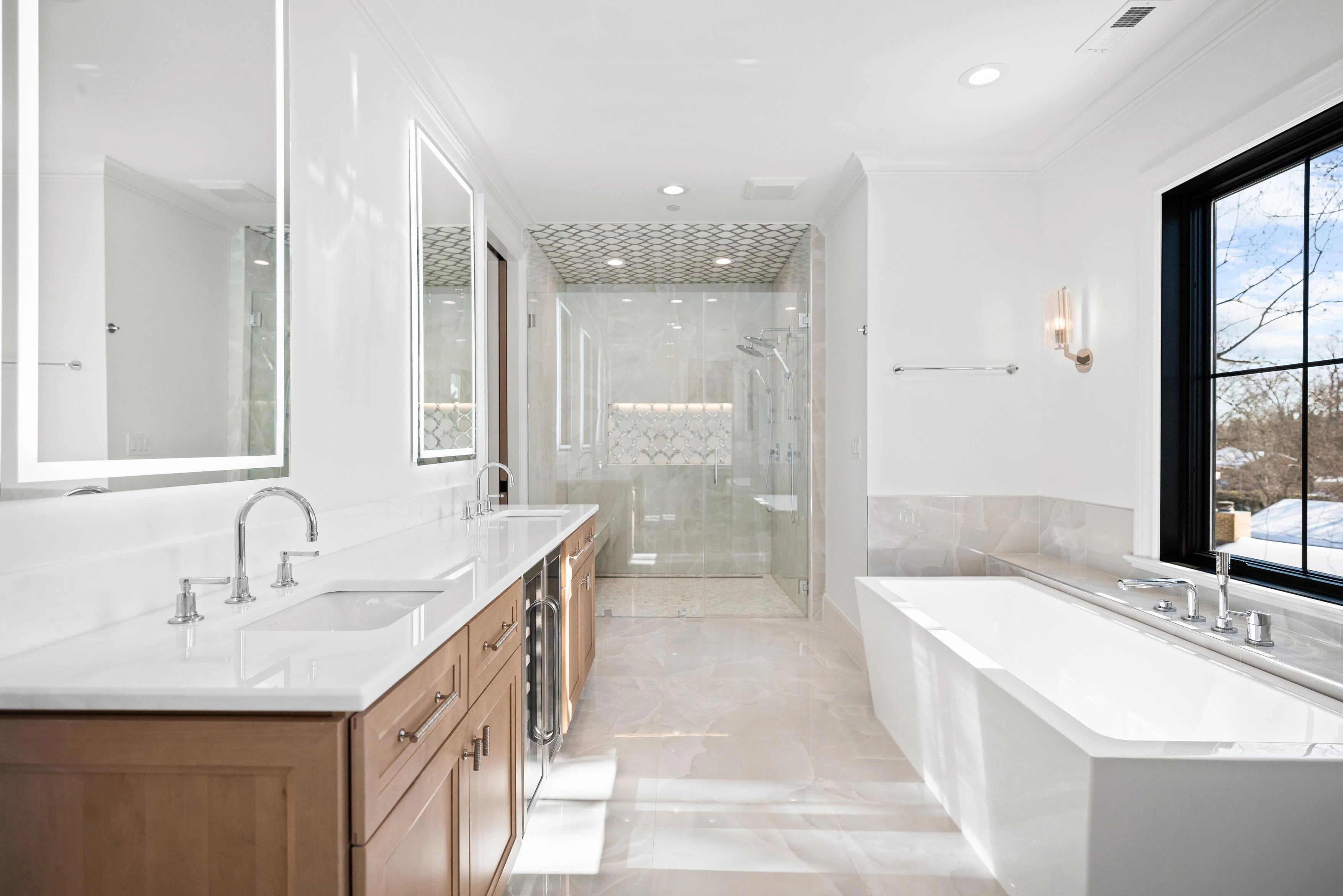 Master bathroom with dual oak vanity, freestanding soaker tub, arabesque tile shower ceiling, and window view