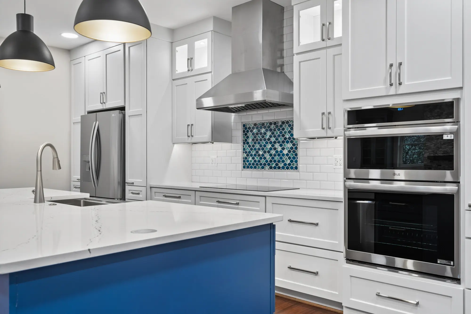 Kitchen with stainless steel LG appliances, blue island, and arabesque tile accent
