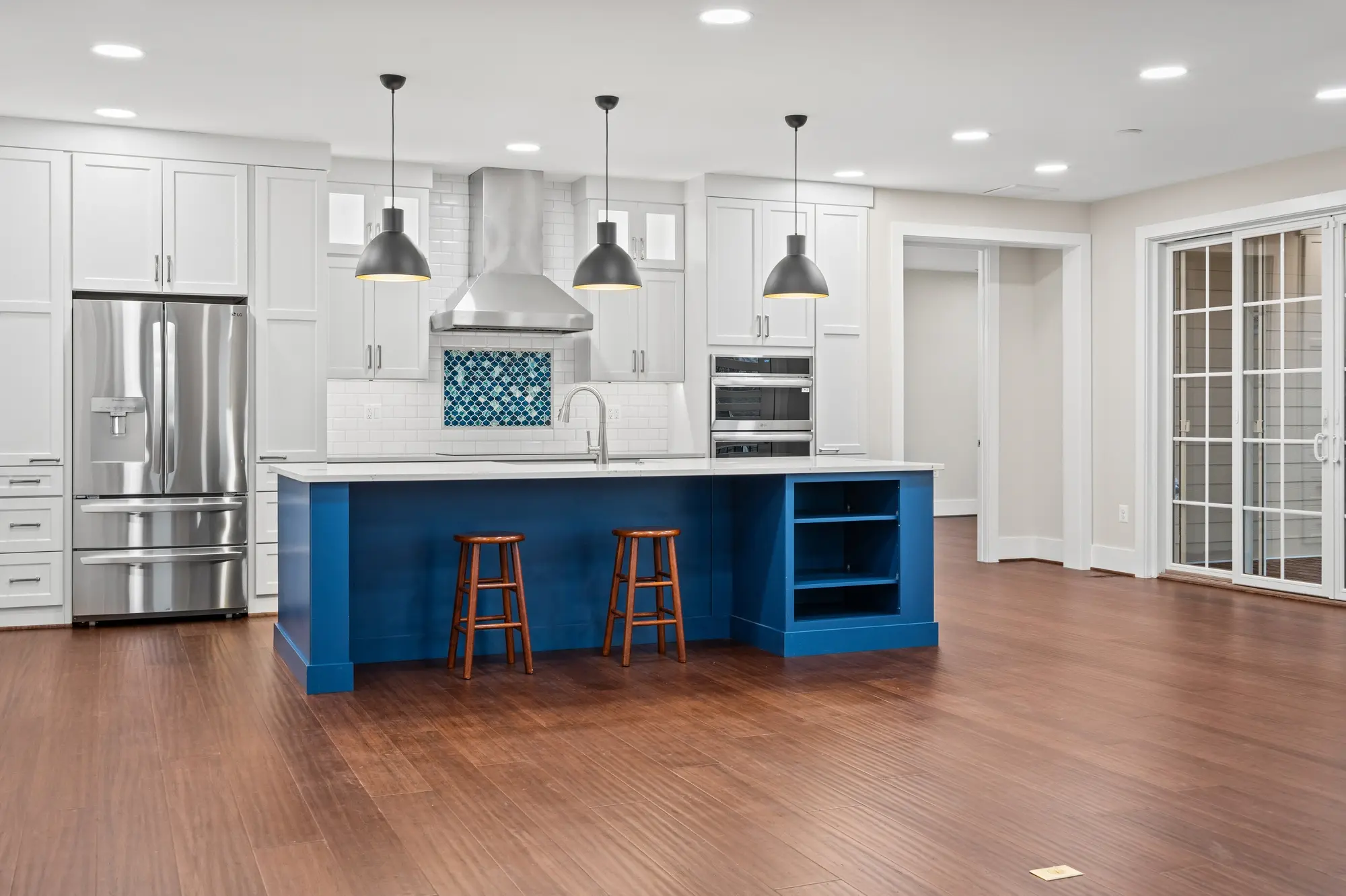 Kitchen overview with white cabinetry, blue island, and open layout
