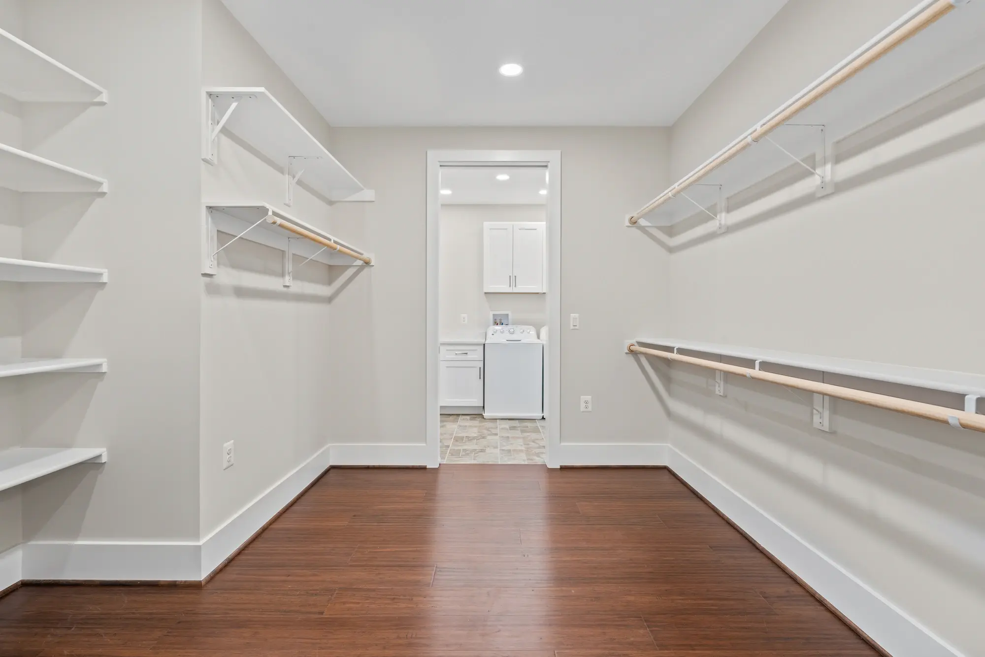 Walk-in closet with view into laundry room with washer and dryer