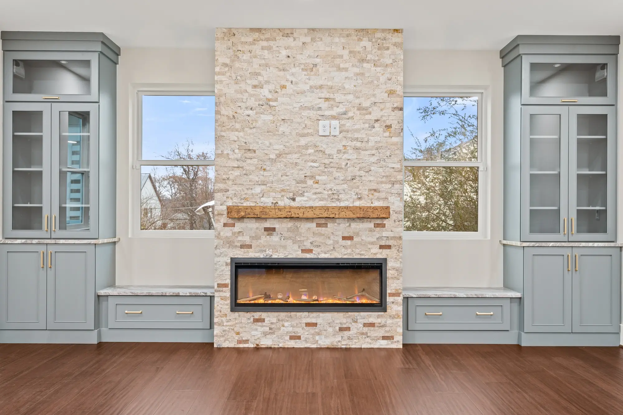 Stone fireplace wall with wood mantel and blue built-in cabinets