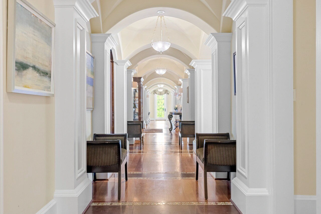 Grand arched hallway with vaulted ceiling, pendant lights, and polished hardwood floors