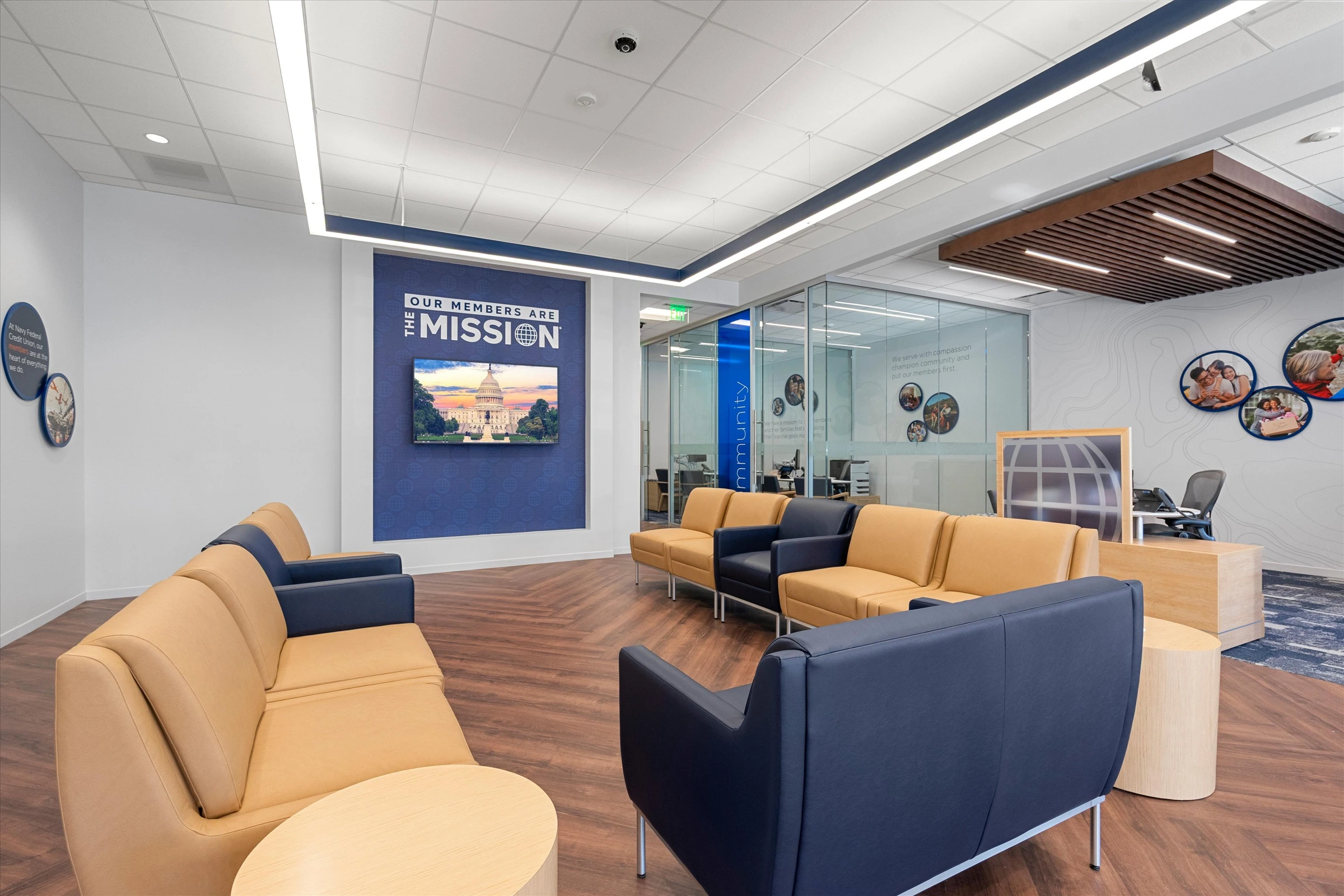 Member lounge with "Our Members Are The Mission" display, navy and gold sofas, circular branded photo displays, wood slat ceiling, and glass-walled Integrity room