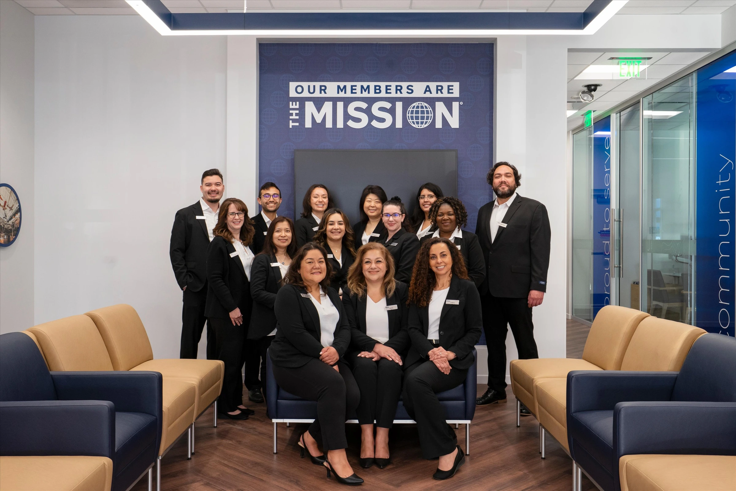 Navy Federal Credit Union Chantilly branch team formal group photo in front of "Our Members Are The Mission" wall display in member lounge