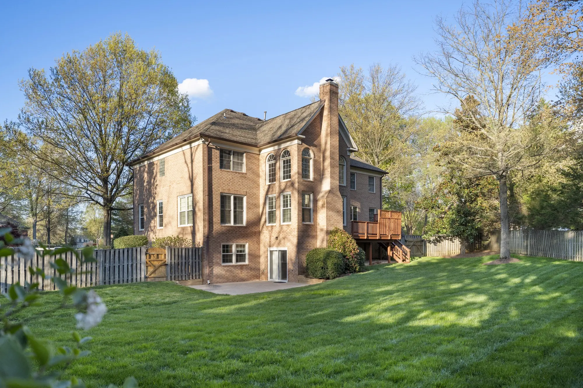 Large fenced backyard and brick exterior rear view