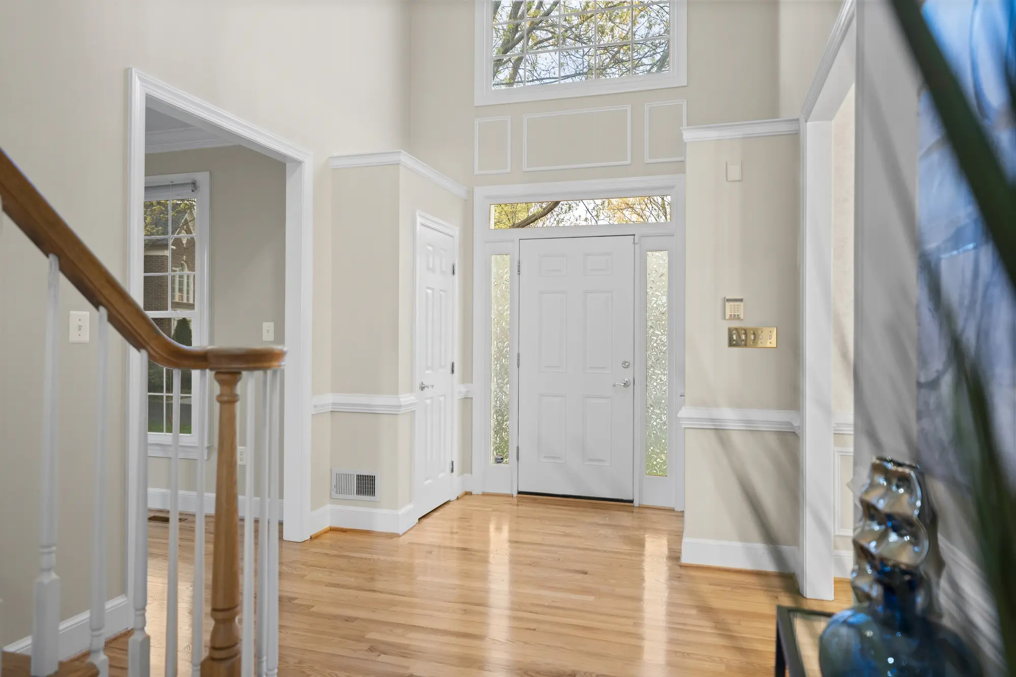 Bright entry foyer with hardwood floors, tall windows, and open staircase