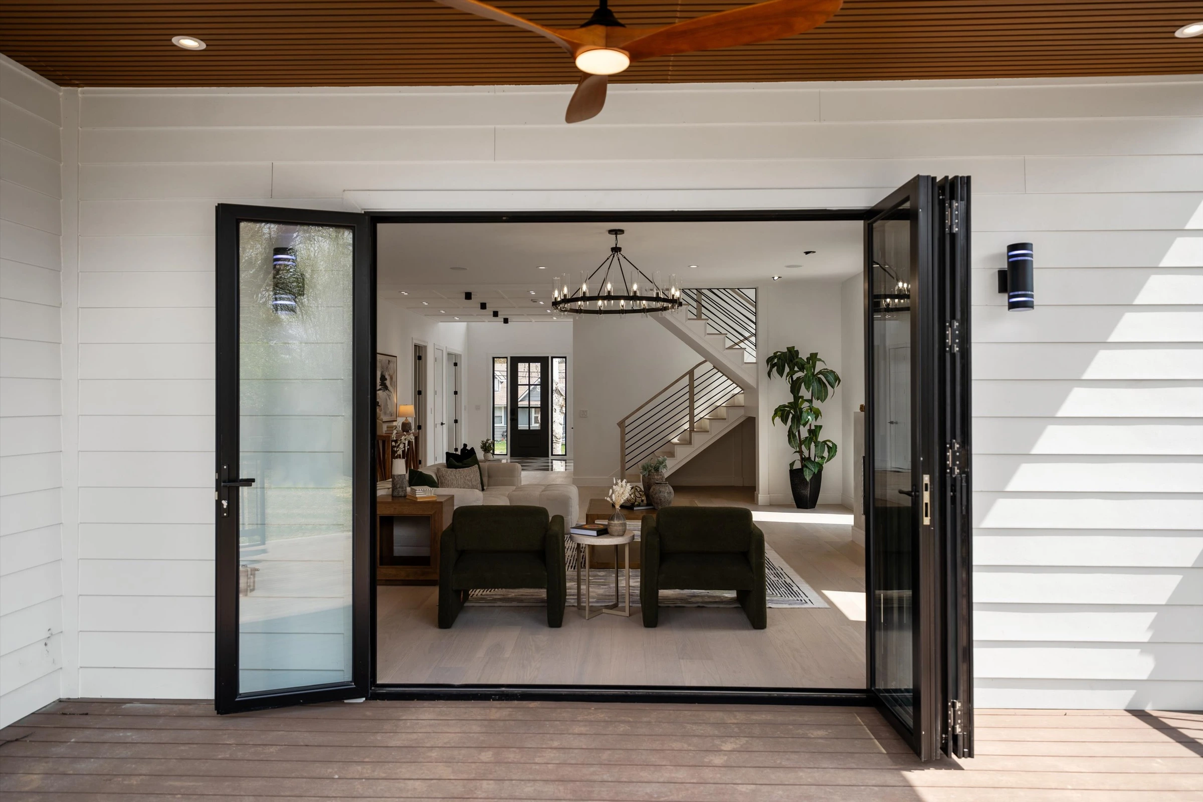 Covered rear patio with wood-plank ceiling, ceiling fan, bi-fold glass doors opening to family room, and composite deck