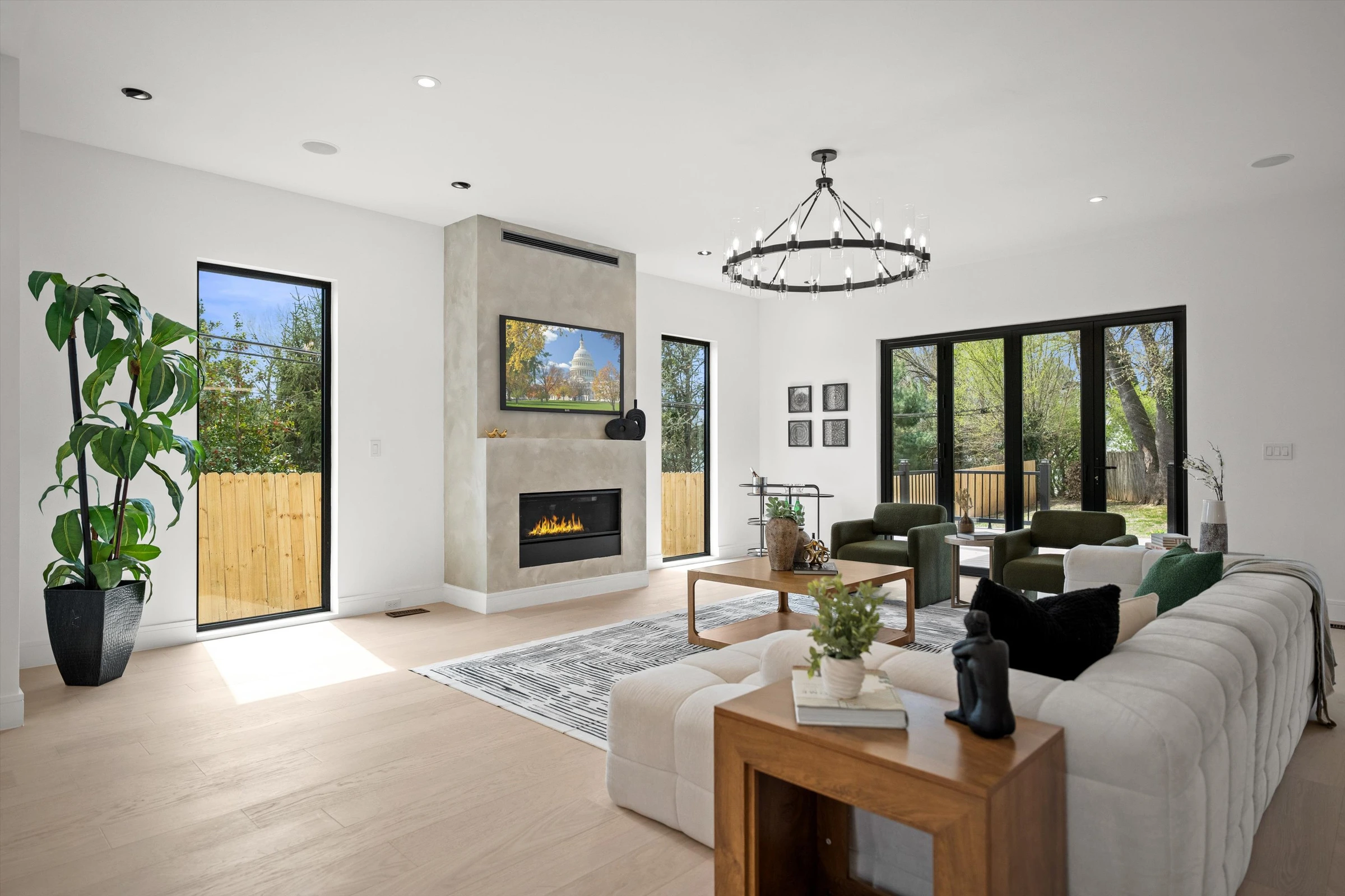Family room with concrete-surround gas fireplace, iron ring chandelier, sliding glass doors to backyard, and green velvet accent chairs