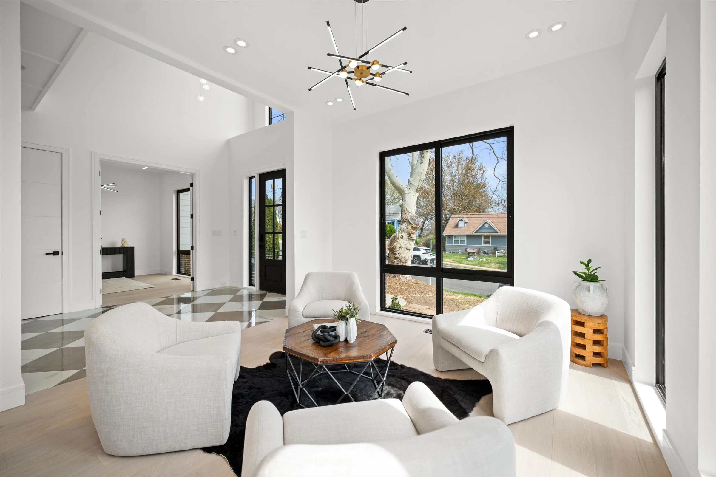 Sitting room wider view showing connection to checkered marble foyer, double-height ceilings, and bright open layout
